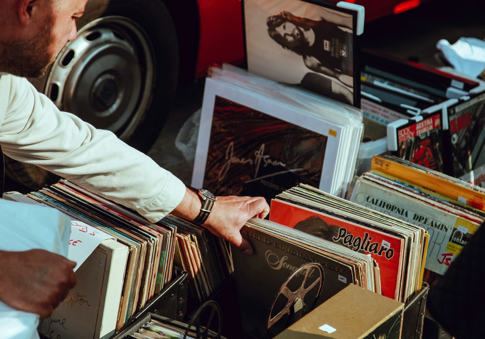 Main qui fouille un bac de disques vinyles d’occasion