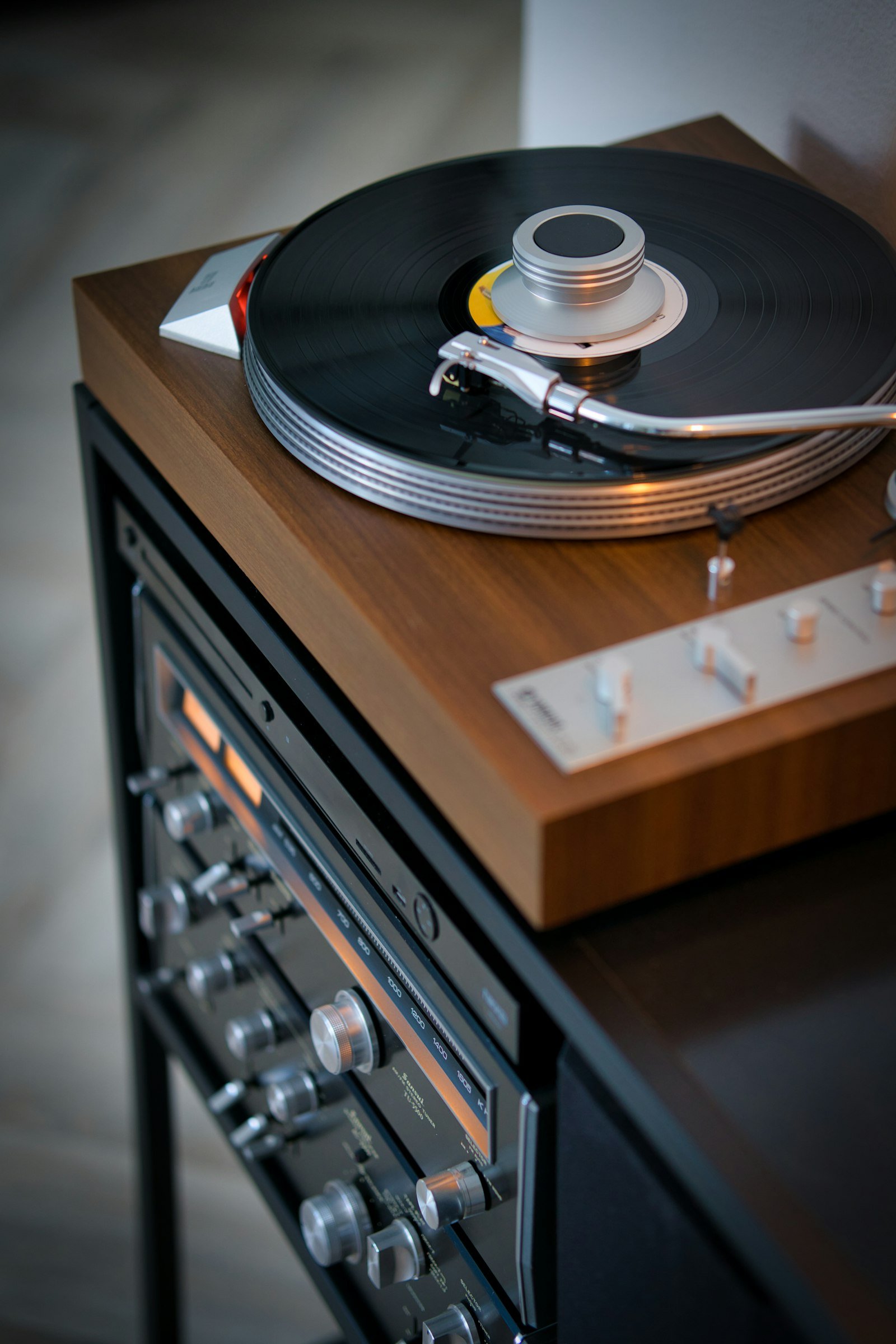 Platine vinyle posée sur un meuble en bois, ampli visible en dessous